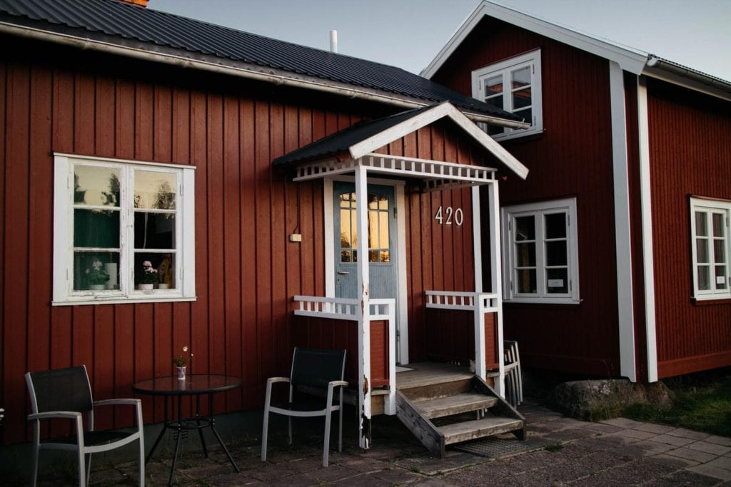 Rött hus med vita fönster och svart plåttak.